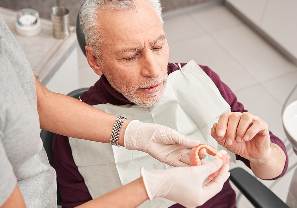 An elderly gentleman at a denture fitting consultation at a dental office.