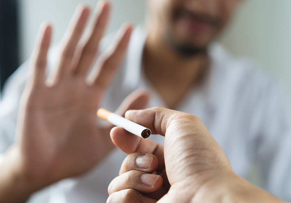 Man avoiding a cigarette being offered to him after an emergency dental procedure
