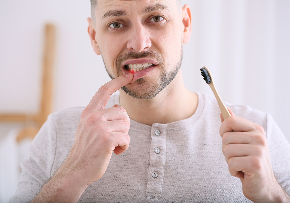 Man holding toothbrush with bleeding gums