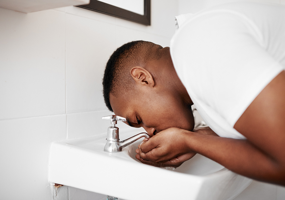 Man rinsing tooth in sink